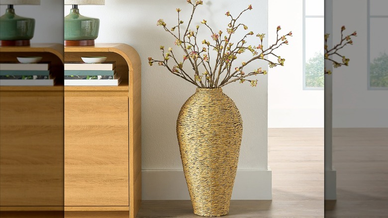 Faux seagrass vase with dried stems inside next to a table