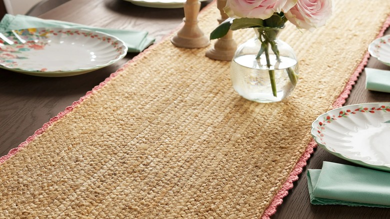 Jute table runner with pink crochet trim on a wood table