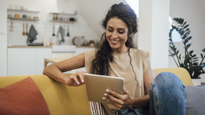 Woman at home sitting on a couch using a digital tablet