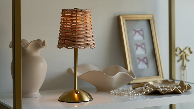 Closeup of a small table lamp with a rattan shade on a bookshelf
