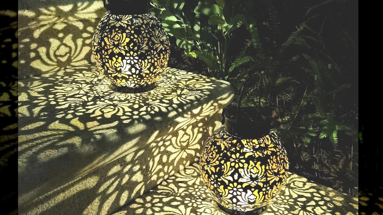 Closeup of two solar lanterns at night sitting on steps