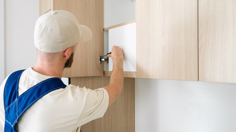 A man installing wood cabinets