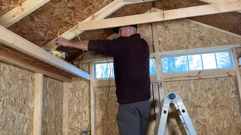 a man installs power in a backyard shed