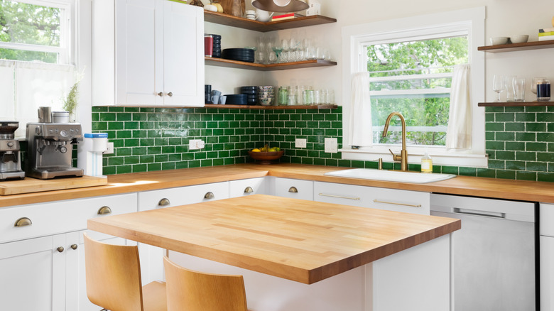 Kitchen with green tiles and butcher block countertop