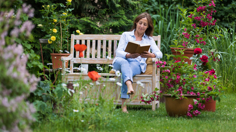 Woman sitting in a garden, reading a book