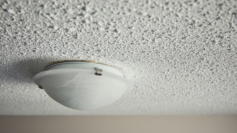 A white domed light fixture attached to a white popcorn ceiling