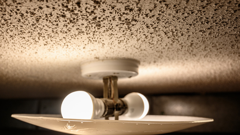 closeup of a popcorn ceiling with light fixture illuminated with two bulbs