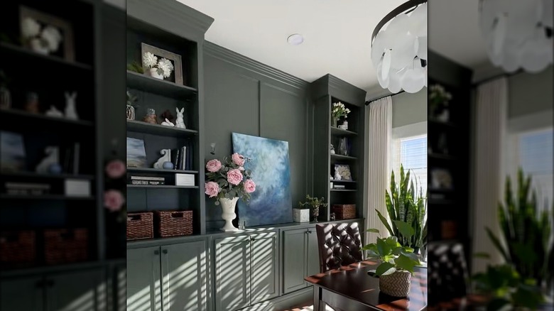 Green built in cabinets with art and decor on them in a study