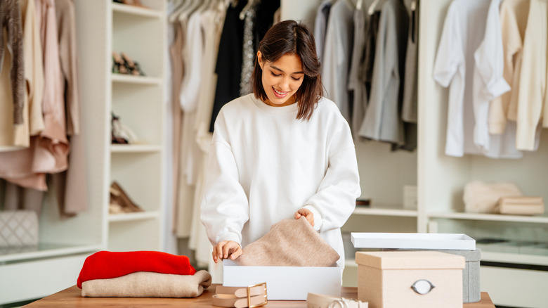 Woman standing in walk-in closet packing clothes