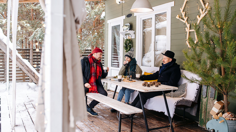 Three people bundled up outside at a table on the patio