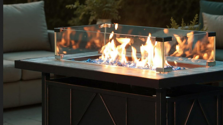 A close-up of the BALI OUTDOORS firepit with glass around it and lit