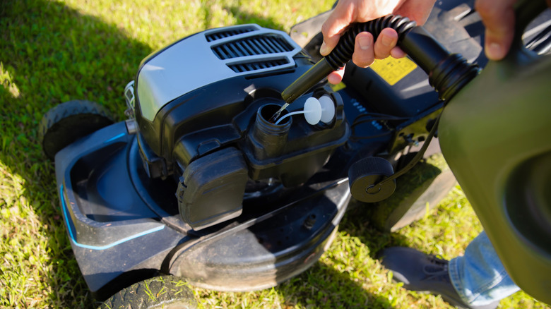 Person filling lawn mower with gas