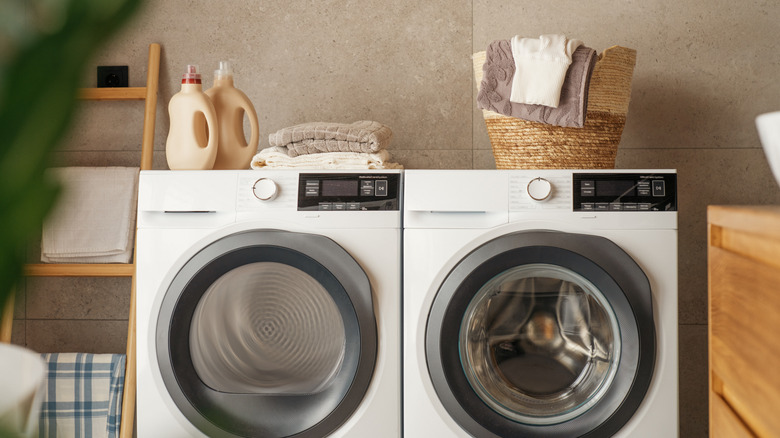 Front-loading washer and dryer with towels on top.