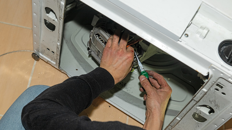 A person's hands fixing the back of a washing machine