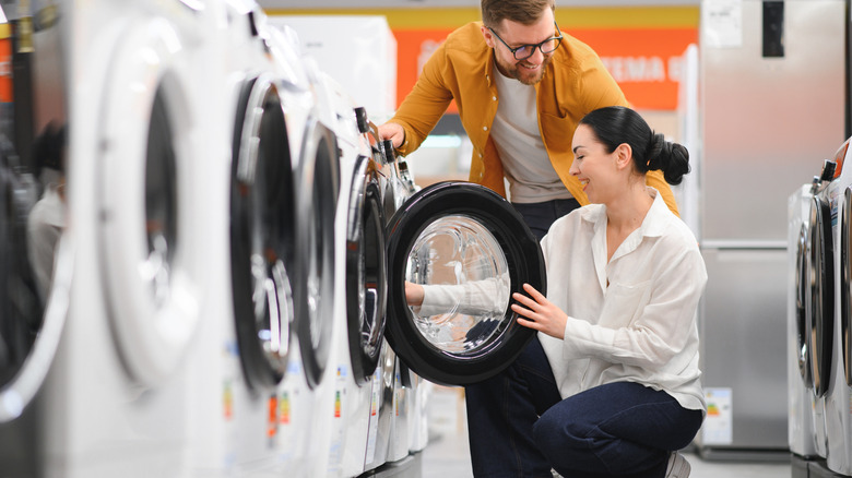 A couple looking at a front-load washing machine in a store