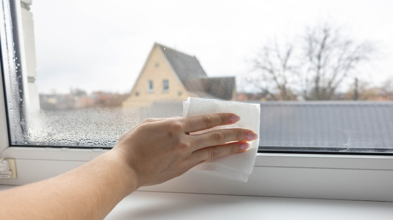 Woman's hand holding a cloth wiping condensation off window