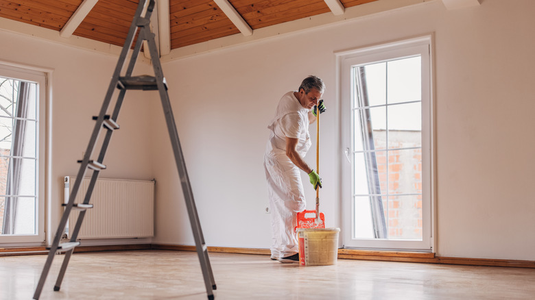 An old man painting a wall