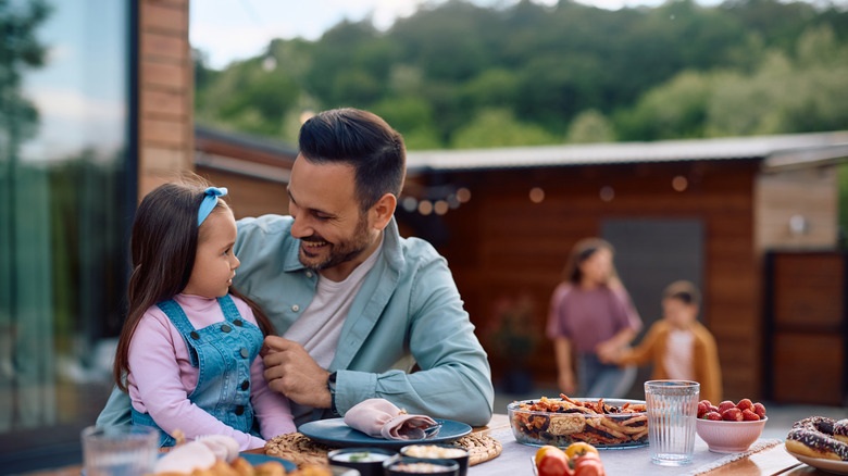 Dad and daughter eating at table on patio