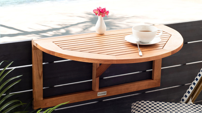 A teak outdoor folding table installed on a balcony rail