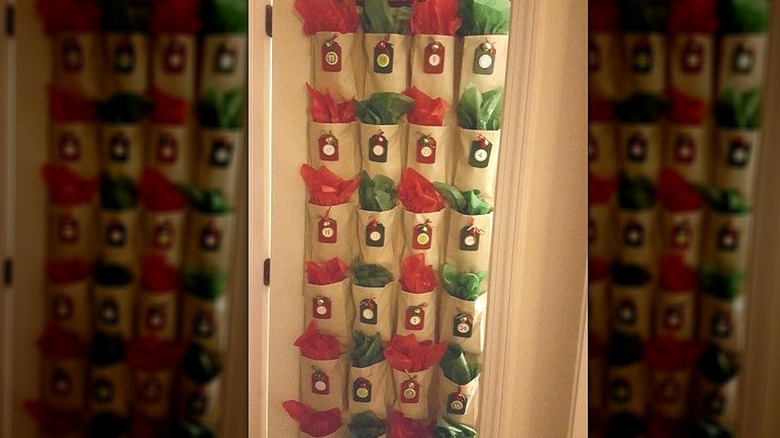 An advent calendar made from an over-the-door shoe holder with number labels and red and green tissue paper