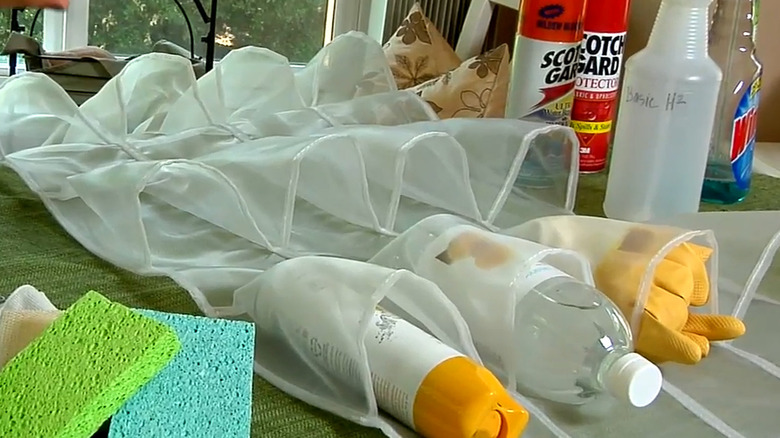 Over-the-shoe holder on a table with cleaning supplies in some pouches and additional cleaning supplies around it