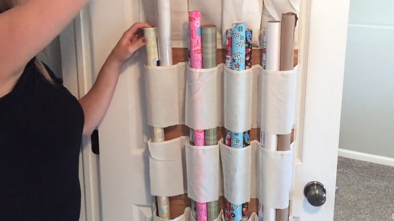 Woman putting a roll of wrapping paper in a modified over-the-door shoe holder