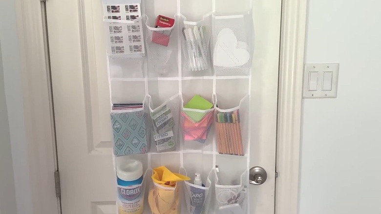 Various office supplies sorted out into the pockets of a mesh shoe storage hanger