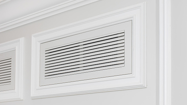 An air vent framed with decorative wooden trim