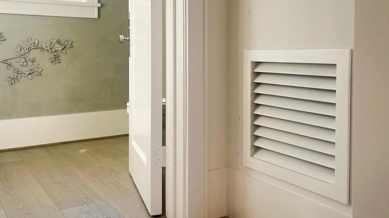 A decorative louvered vent cover on a wall