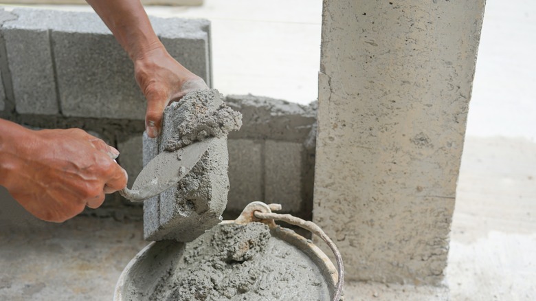 construction worker lays bricks with cement