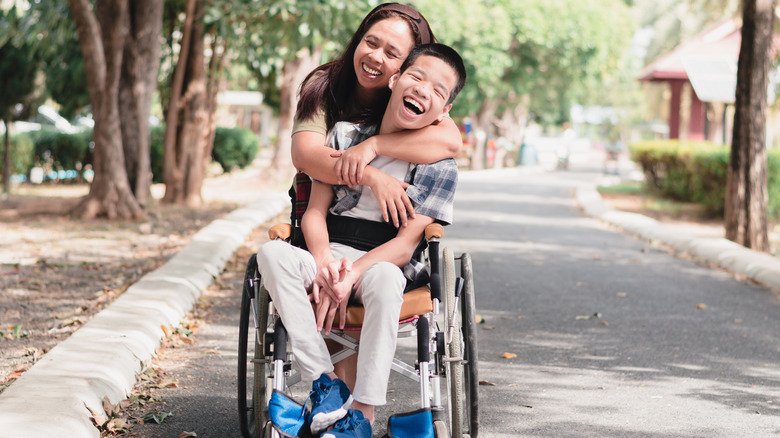 woman hugging boy in wheelchair