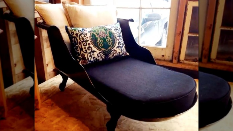 dark colored chaise made from a claw foot tub with white throw pillows and a small throw pillow with intricate designs