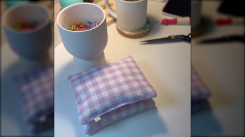 A puple and white gingham drawer sachet sits on a craft table surrounded by crafting tools.