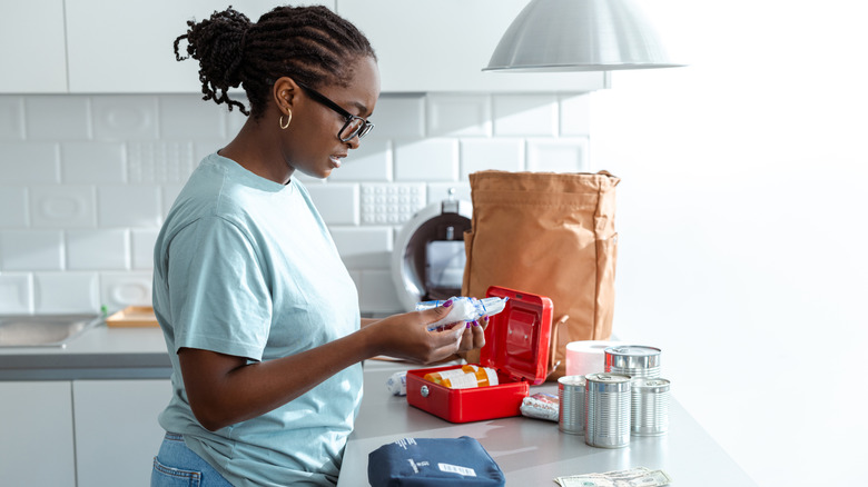 A woman looks through emergency supplies on her kitchen counter before placing in a drawstring bag.