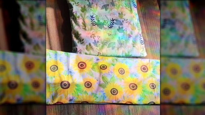 Two homemade heating pads in floral fabric sit on a table