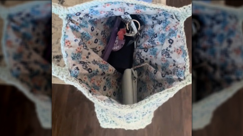 A crochet purse is pulled open to reveal a cute floral liner and the purse's contents.