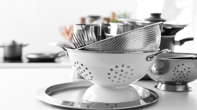 A close up of a few different colanders on kitchen counter