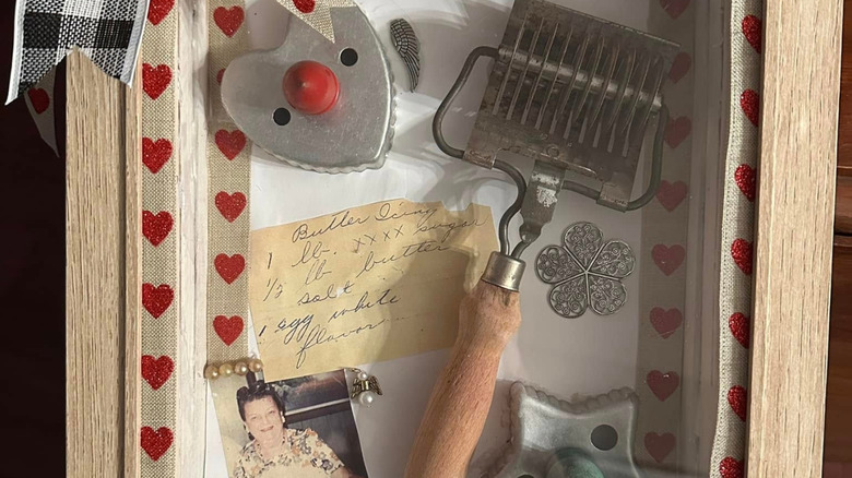 Close-up of a shadow box with cookie cutters, a hand-written recipe, and a photo