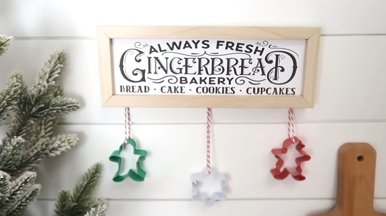 Winter gingerbread bakery sign with three cookie cutters dangling from the bottom