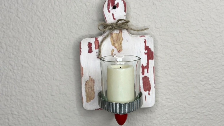 Mini cutting board and cookie cutter candle holder hanging on a textured white wall
