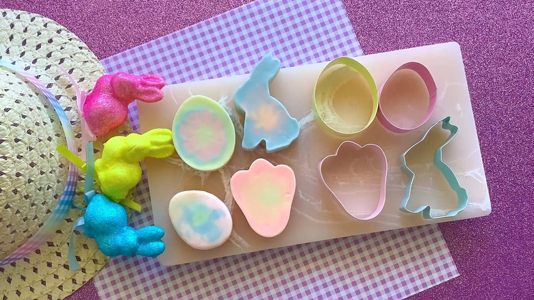 Easter egg, bunny, and flower soaps with cookie cutters used as the molds next to the soap