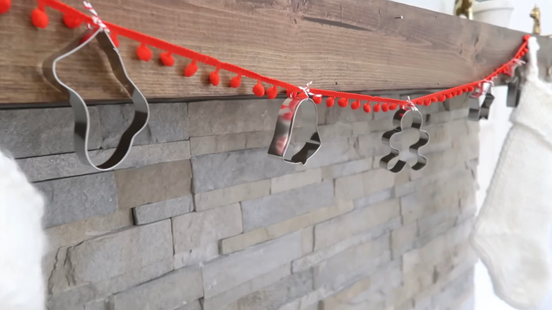 Close-up of a Christmas garland made with pompom ribbon and metal cookie cutters tied onto it