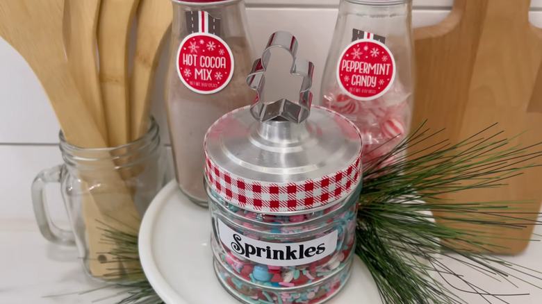 Jar filled with sprinkles with a small gingerbread cookie cutter glued to the top as a handle
