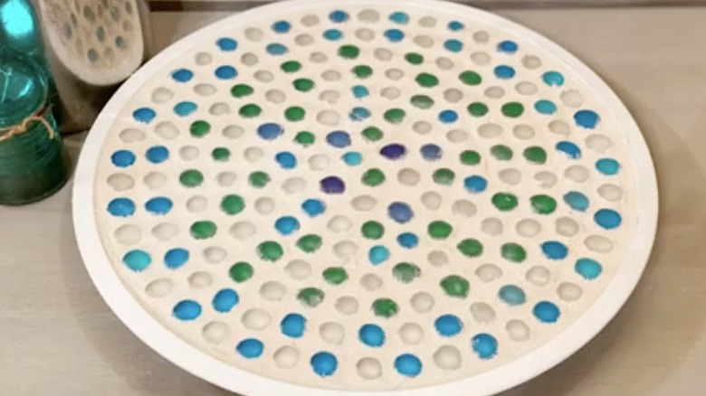 A white Lazy Susan tray is covered in blue and green mosaic tiles.