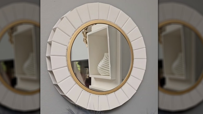 A modern white and gold wall mirror.