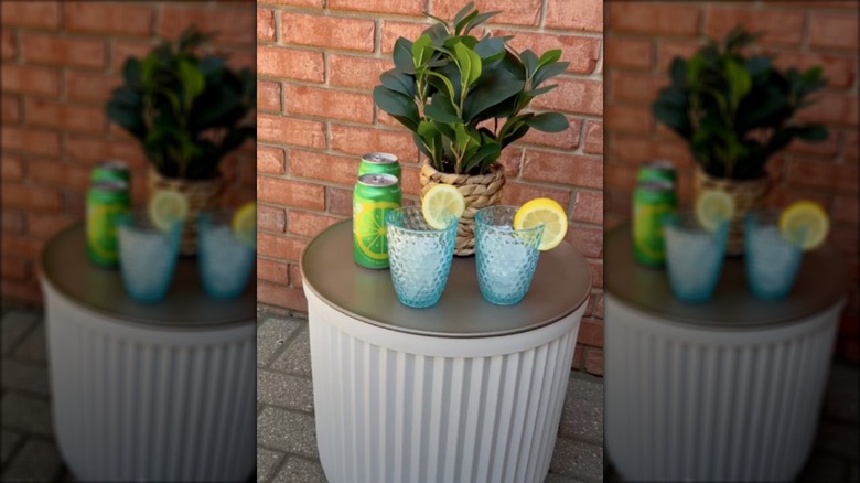 A large planter has been turning into an outdoor drinks table with a gold-painted pizza pan as the lid.