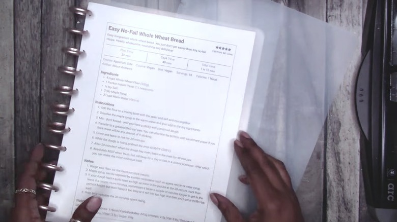 A person putting clear cover on recipe binder
