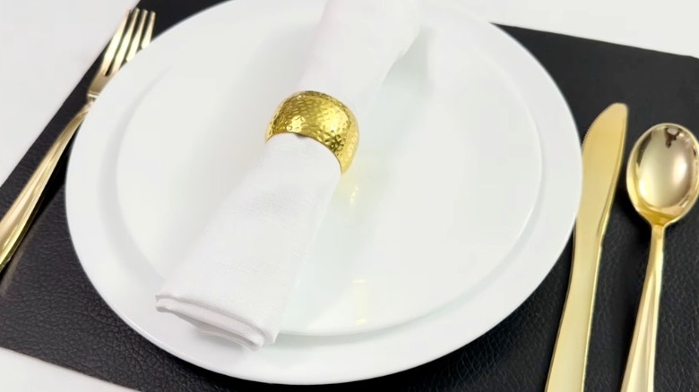 White dinner plates with gold flatware on DIY placemat with black leather cover