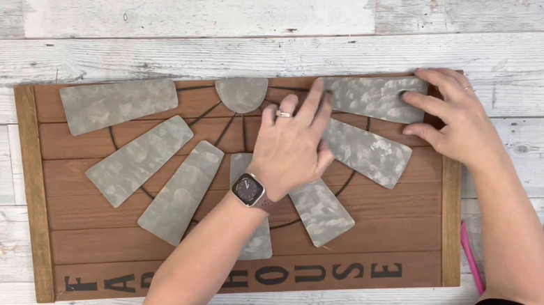 A person putting imitation metal features on farmhouse wall decor