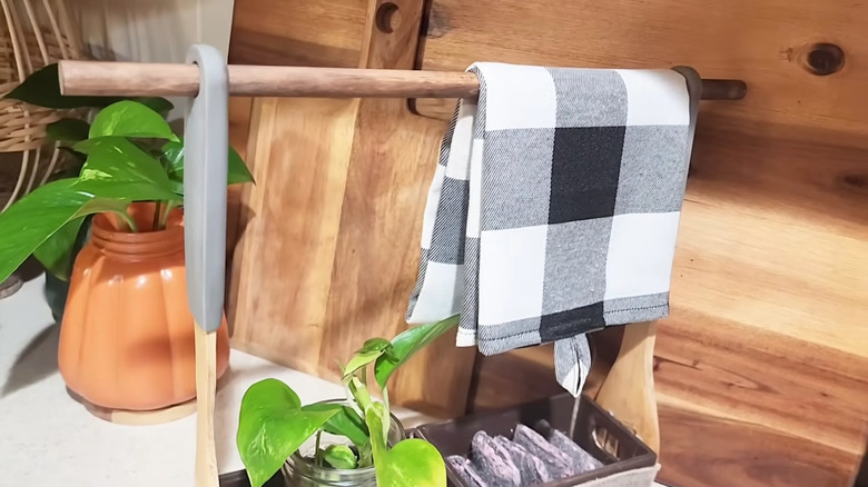 Wood towel hanger made with mini crates, a dowel, and cooking utensils holds blanks, tea, and a black and white towel